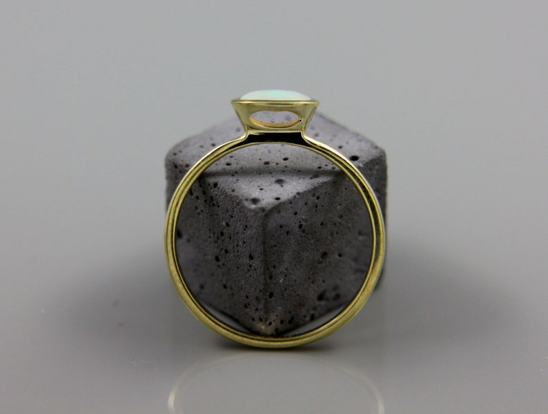 May include: A gold ring with a light blue opal gemstone set in a bezel setting.