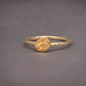 May include: A gold ring with a textured, round, hammered design.