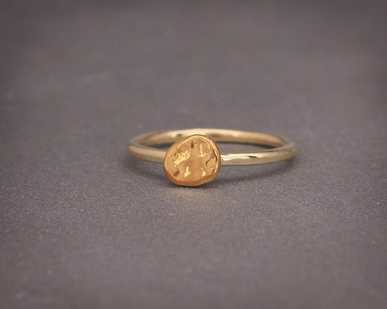 May include: A gold ring with a textured, round, hammered design.