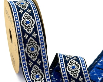 Puede incluir: Un carrete de cinta azul y plata con un patrón repetido de flores plateadas y puntos azules. La cinta tiene un borde de flecos.