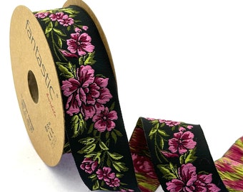 Puede incluir: Un carrete de cinta negra con un patrón floral rosa y verde. La cinta está envuelta alrededor de un carrete de cartón marrón con la palabra "fantastic" impresa en él.