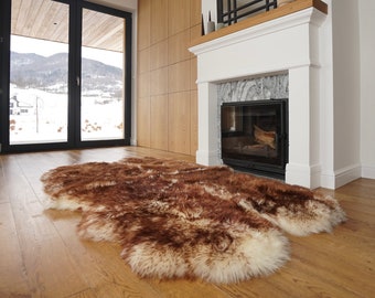 May include: A large, rectangular sheepskin rug featuring a thick, long-pile texture with a natural color gradient. The fur displays a blend of deep chocolate brown and creamy white tones, creating a variegated appearance across the entire surface.