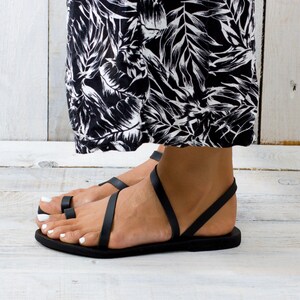Side view of the black sandal. Shows the thin, durable rubber outsole and the open-back, easy slip-on style.