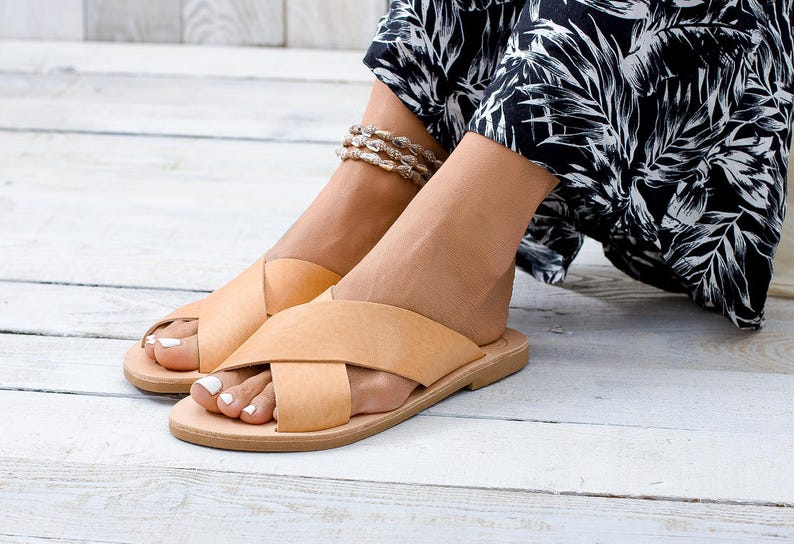 May include: A pair of tan leather sandals with criss-cross straps. The sandals have a simple design and are perfect for summer.