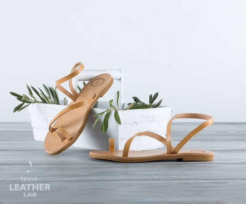 natural tanned leather sandals Syros details of flat leather footbed and straps standing on a basket with olive branch with leaves.