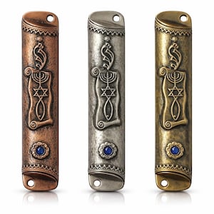 May include: Three metal mezuzah cases in copper, silver, and gold tones. Each case features an embossed design of a menorah, Star of David, and scroll, with a blue gemstone at the base. The cases have a hole at the top for hanging.