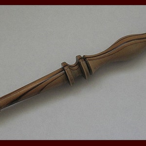 Könnte beinhalten: Ein Kalligraphie-Stift aus Holz mit einer dekorativen handförmigen Spitze und einem gestreiften Holzgriff. Der Griff hat oben einen dekorativen Knopf.