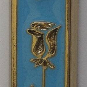 May include: A gold-colored mezuzah with a blue background. The mezuzah features a Star of David, the Hebrew letter Shin, and a stylized rose.