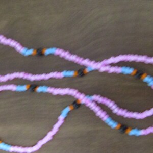 May include: A pink and blue beaded necklace with black and orange beads.