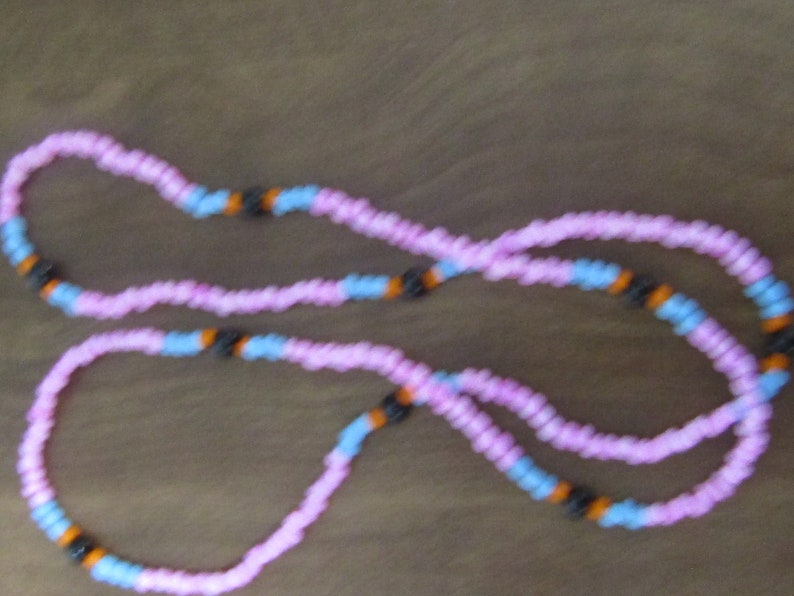May include: A pink and blue beaded necklace with black and orange beads.