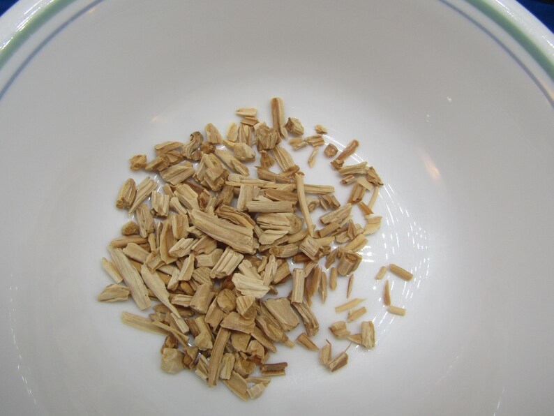 May include: A white bowl filled with light brown wood chips. The chips are small, rectangular pieces, varying in size and shape. The bowl has a green and blue rim.
