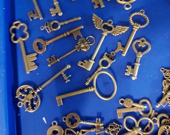 May include: A collection of antique-style skeleton keys in various shapes and sizes, including winged, heart, and clover designs. The keys are arranged on a blue surface.