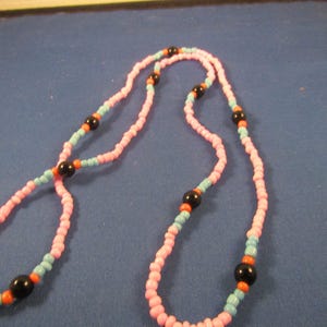 May include: A pink and blue beaded necklace with black and orange beads.