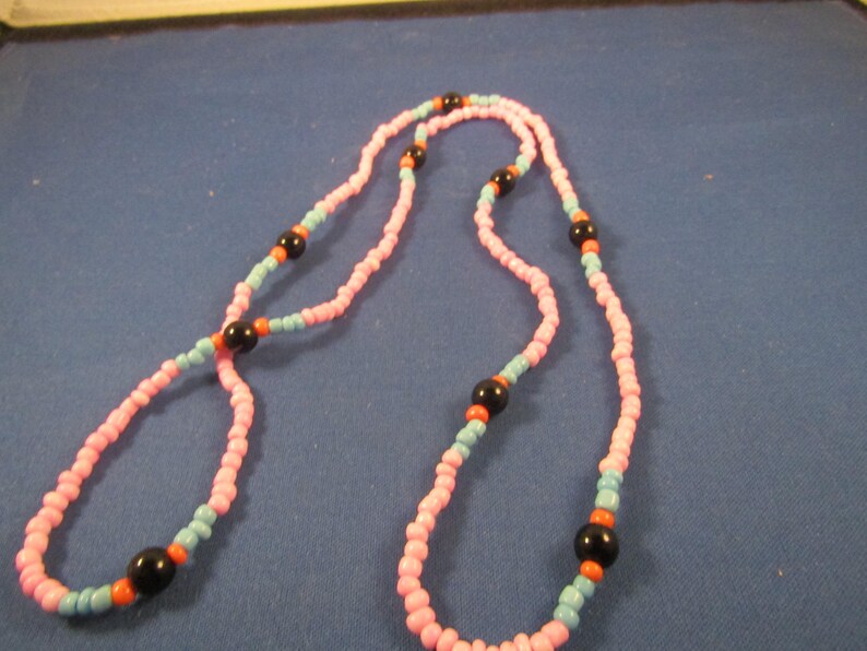May include: A pink and blue beaded necklace with black and orange beads.