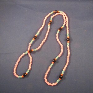 May include: A pink and blue beaded necklace with black beads. The necklace is made of small, round beads and is approximately 76 cm long.