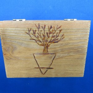 May include: A wooden box with a hinged lid. The box is decorated with a woodburned design of a tree in a pot.