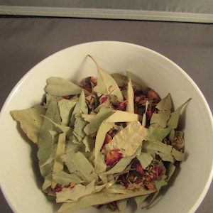 May include: A white bowl filled with dried eucalyptus leaves and rose petals.