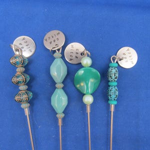 May include: Four silver stitch markers with turquoise and green beads. The stitch markers are labeled "Sea Witch", "Sea Witch", "Sea Witch", and "Sea Witch".