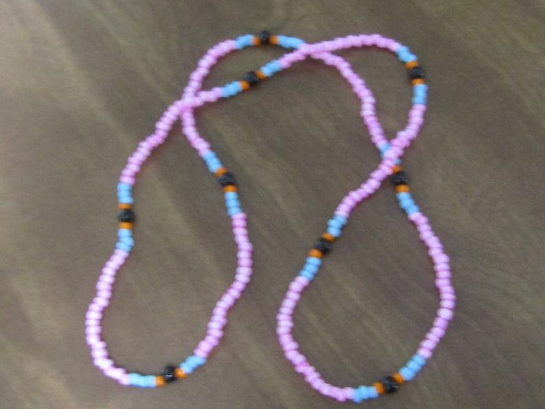 May include: A pink and blue beaded necklace with black beads interspersed throughout.