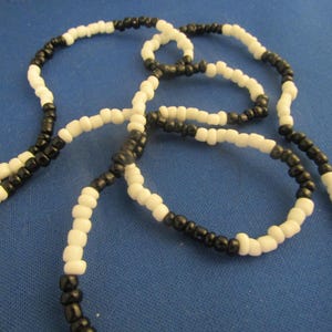 May include: A black and white beaded necklace with multiple strands. The beads are small and round.
