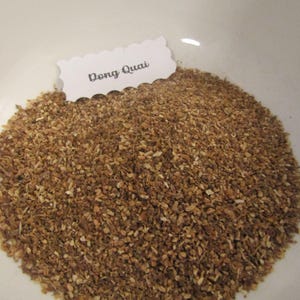 May include: A white bowl filled with Dong Quai, a brown, dried herb.