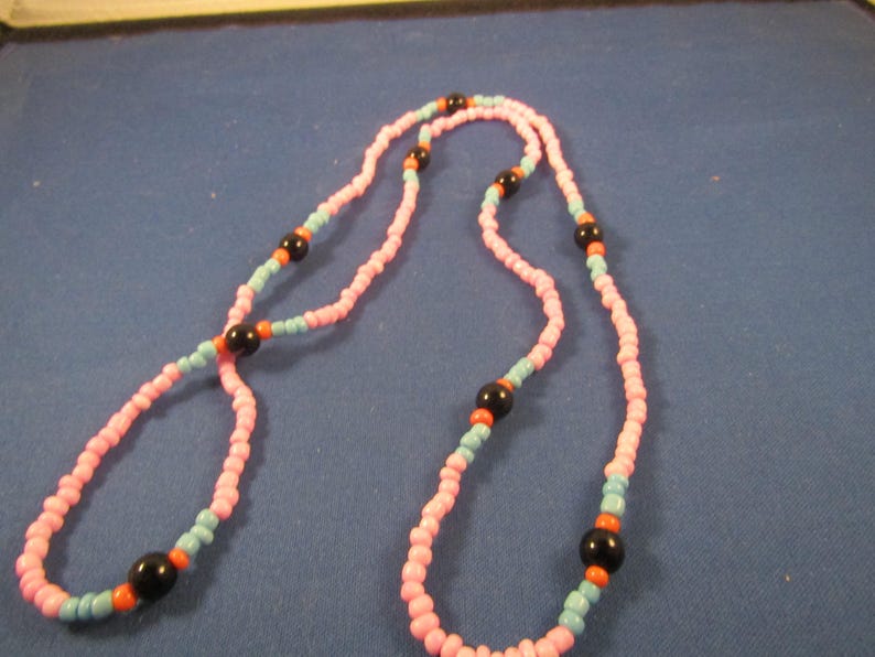 May include: A pink and blue beaded necklace with black and orange beads.