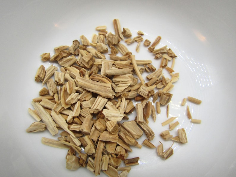 May include: A close-up shot of wood chips, varying in size and shape, scattered across a white surface. The chips are primarily light brown with some darker streaks, suggesting different wood types. Ideal for smoking or grilling.