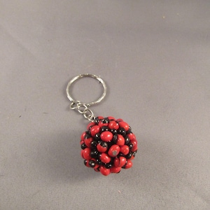 May include: A red and black beaded keychain with a silver key ring.