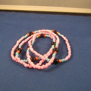 May include: A multi-strand beaded necklace with pink, blue, black and orange beads.