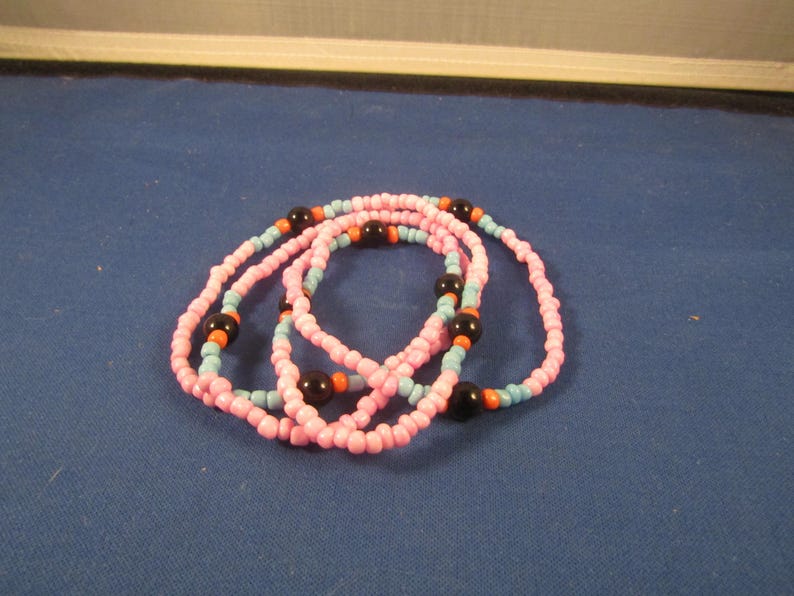 May include: A multi-strand beaded necklace with pink, blue, black and orange beads.
