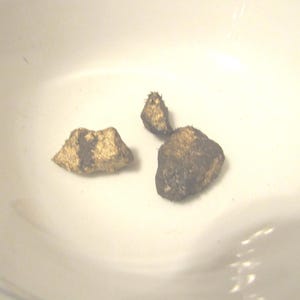 May include: Three small, irregular, textured nuggets with a metallic gold finish and dark brown accents. These solid, rock-like pieces have a rough, uneven surface and are displayed together, showing a distinct contrast between the gold and dark tones.