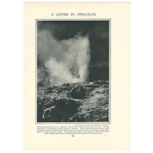May include: Black and white photograph of a geyser erupting. The image is titled "A Geyser in Operation." The geyser is spewing a column of water and steam into the air. The surrounding landscape appears rocky and barren.