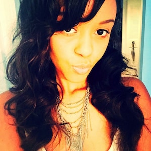 May include: A woman with long, dark brown hair wearing a white tank top and a silver chain necklace with multiple strands.