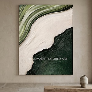 Op de afbeelding: Een rechthoekig schilderij op canvas met een dikke, gelaagde impasto-textuur. De compositie is verdeeld in drie secties: een saliegroen bovengedeelte, een centrale crèmekleurige diagonale band en een donker bosgroen benedengedeelte. De tekst luidt HANDMADE TEXTURED ART.