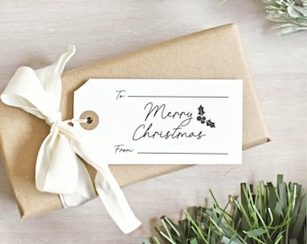May include: A wrapped gift in brown paper with a white tag and cream ribbon. The tag reads "Merry Christmas" with holly accents. The gift is surrounded by green and white decorative foliage, perfect for the holiday season.
