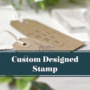 May include: A close-up of a custom designed stamp with a brown paper tag. The stamp features a simple floral design and the text "Custom Designed Stamp".