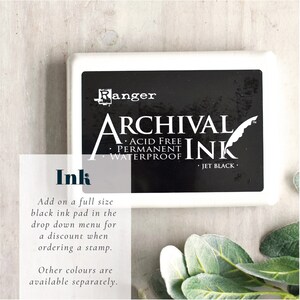 May include: A rectangular, white ink pad with the words "ARCHIVAL INK" in large, bold letters. The ink pad is black and labeled "JET BLACK." The brand name "Ranger" is at the top. The image also includes the word "Ink" and additional text.