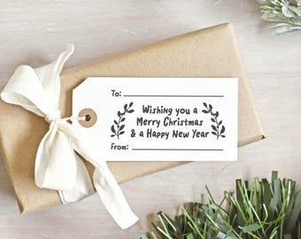 May include: A wrapped gift in brown paper with a white tag and a cream-colored ribbon. The tag reads "Wishing you a Merry Christmas & a Happy New Year" with space for "To:" and "From:" and is decorated with leaf sprigs.