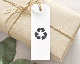 Könnte beinhalten: Ein weißes Geschenkanhänger mit einem schwarzen Recycling-Symbol auf einem braunen Papierpaket, das mit Schnur gebunden ist.