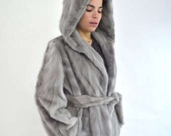 Real sapphire mink fur coat with hood and belt. Genuine mink stroller in gray, unique jacket from premium mink skins, farming fur pelts.