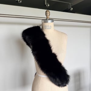 May include: A black fur stole draped over a mannequin. The stole is made of soft, dark fur and is displayed on a vintage-style mannequin with the text "Royal Form" and "Collapsible Model 2000".