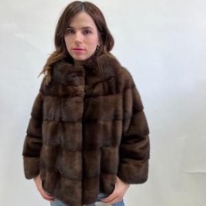 K&ouml;nnte beinhalten: Eine braune Pelzjacke mit Kragen und Knopfleiste. Die Jacke ist aus weichem, luxuri&ouml;sem Pelz gefertigt und hat ein elegantes, modernes Design.