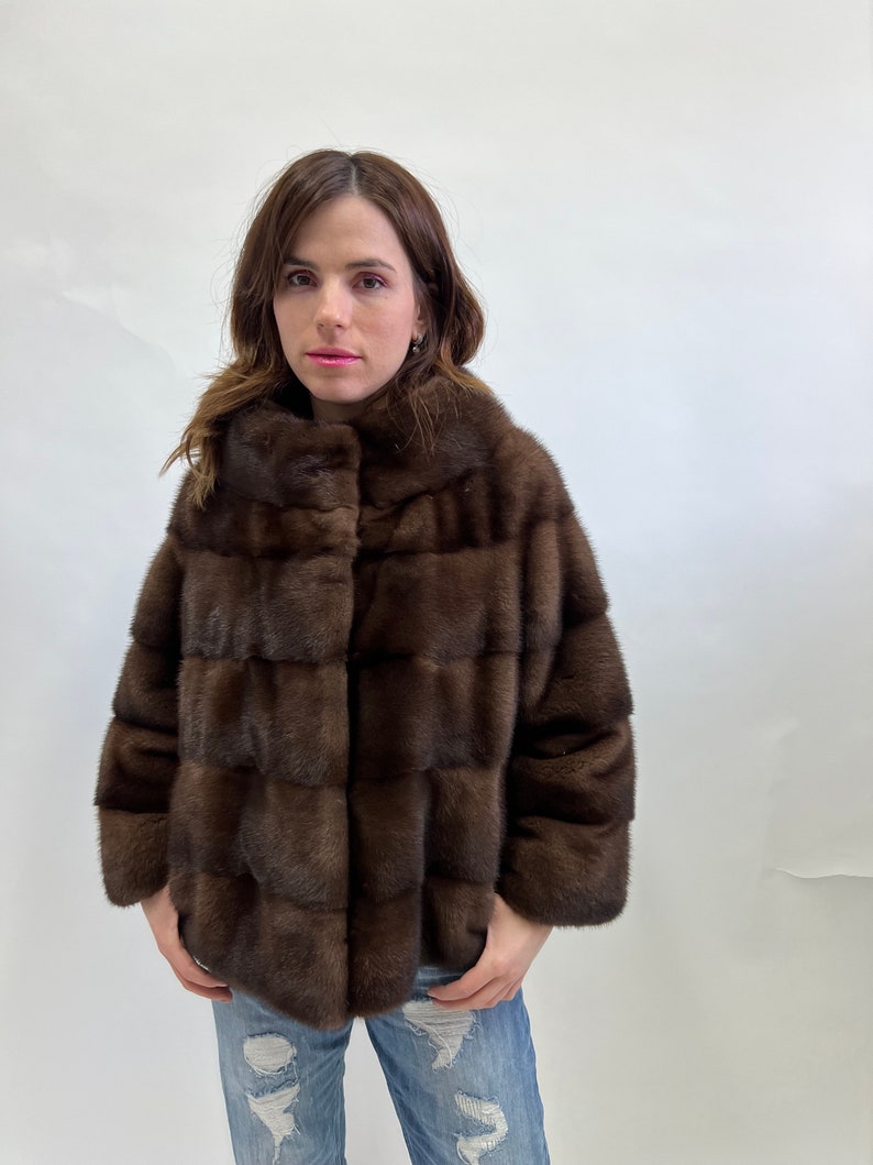 K&ouml;nnte beinhalten: Eine braune Pelzjacke mit Kragen und Knopfleiste. Die Jacke ist aus weichem, luxuri&ouml;sem Pelz gefertigt und hat ein elegantes, modernes Design.