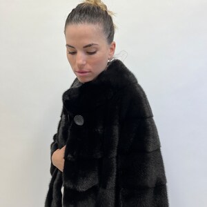 May include: A black fur coat with a button fastening. The coat is made from a soft, luxurious fur and has a classic, elegant style.