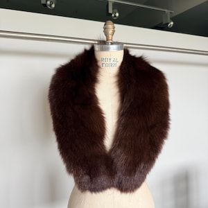 May include: A luxurious brown fur collar displayed on a vintage dress form. The collar is a rich, dark brown color, with a soft, plush texture. The dress form has the text "ROYAL FORM" printed on it.