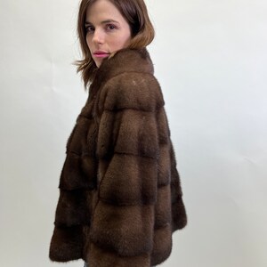 K&ouml;nnte beinhalten: Eine braune Pelzjacke mit Stehkragen. Die Jacke ist aus weichem, luxuri&ouml;sem Pelz gefertigt und hat eine figurbetonte Silhouette.