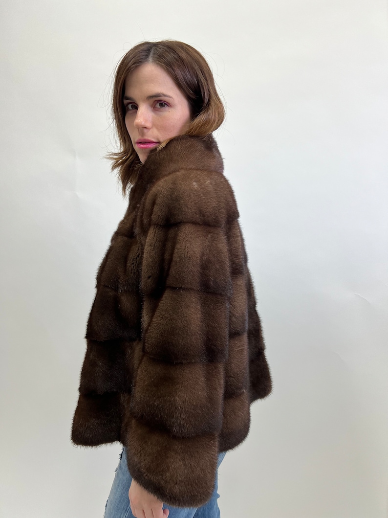 K&ouml;nnte beinhalten: Eine braune Pelzjacke mit Stehkragen. Die Jacke ist aus weichem, luxuri&ouml;sem Pelz gefertigt und hat eine figurbetonte Silhouette.