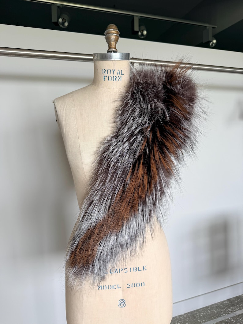 May include: A luxurious fur collar displayed on a mannequin. The collar features a blend of brown, silver, and dark brown fur. The mannequin is a neutral beige color, with the text "ROYAL FORM" and "LAPSBILE MODEL 2000" printed on it.