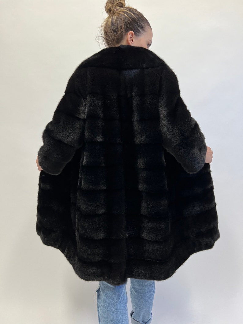 May include: A black fur coat with a long, flowing silhouette. The coat is made of soft, luxurious fur and has a classic, elegant design.