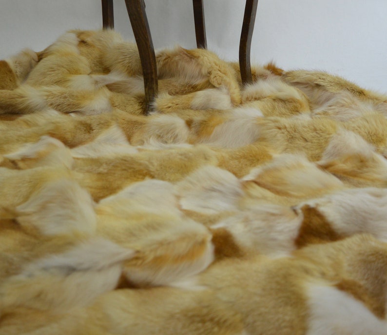 Op de afbeelding: Een luxe wollen deken gemaakt van vossenbont. De vacht is zacht, goud-bruin van kleur en is in een willekeurig patroon gerangschikt. De deken is perfect om elke kamer een vleugje elegantie te geven.